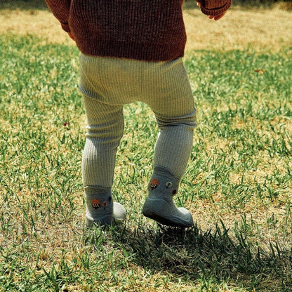 Pequeno a andar sobre a relva, com meias Attipas Woodland Blue Squirrel, promovendo liberdade de movimento e equilíbrio.
