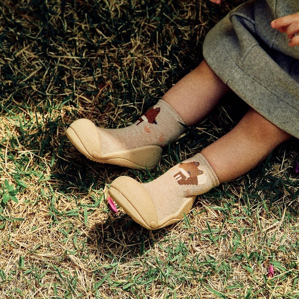 Meias Attipas Woodland Beige Fox em criança, promovendo liberdade de movimento e equilíbrio desde os primeiros passos.