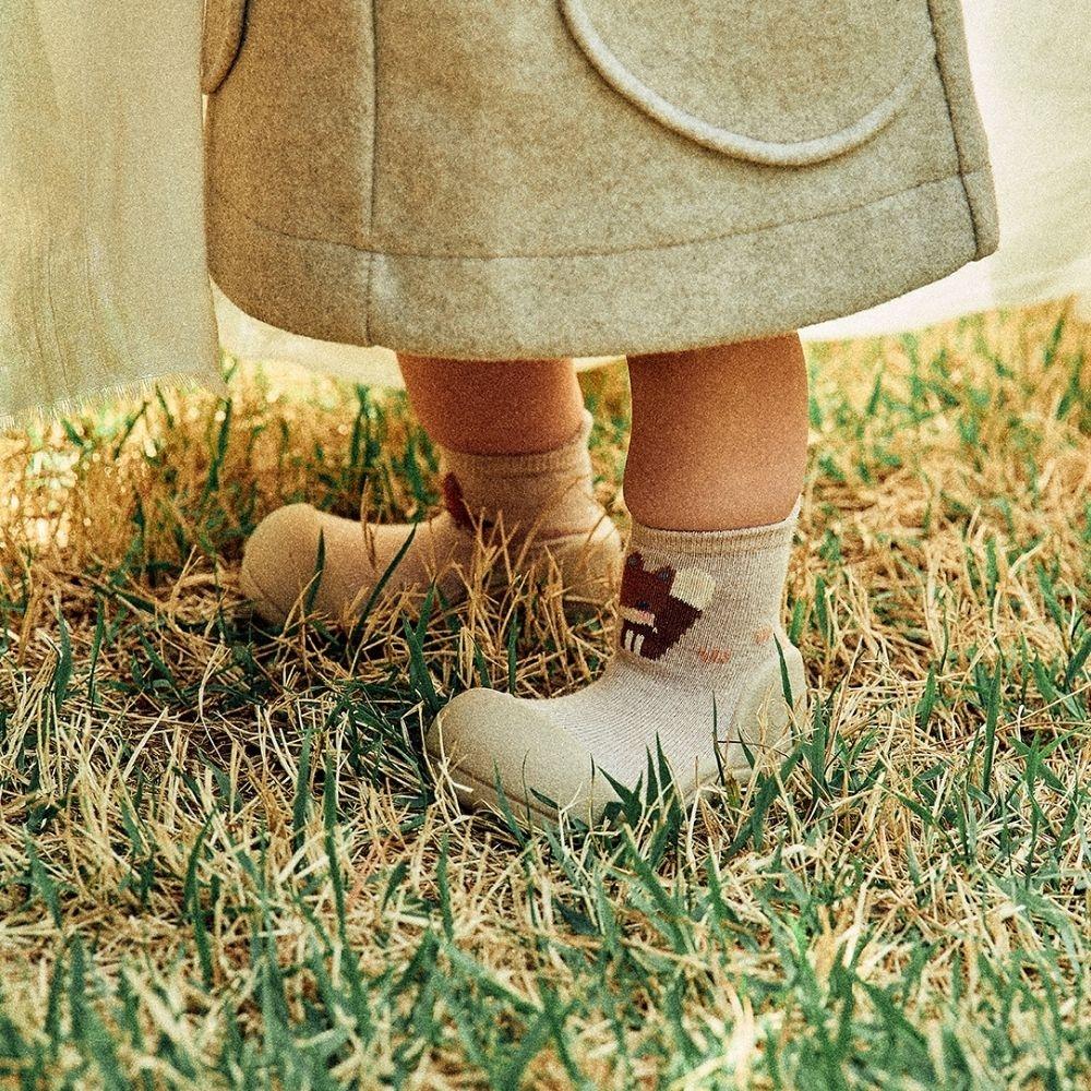Pequenos pés a usar as meias Attipas Woodland Beige Fox, desenhadas para promover o desenvolvimento natural das crianças.