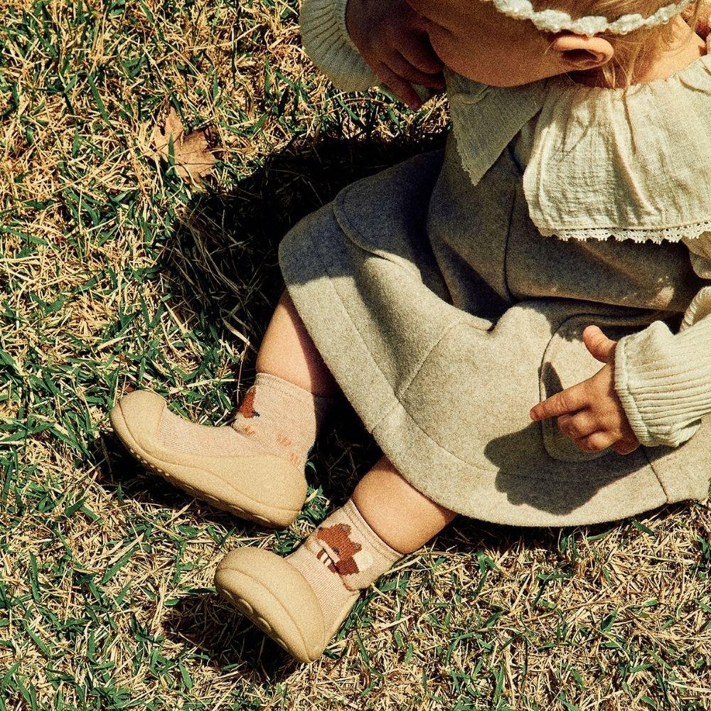 Criança a usar meias Attipas Woodland Beige Fox no campo, promovendo liberdade de movimento e conforto.
